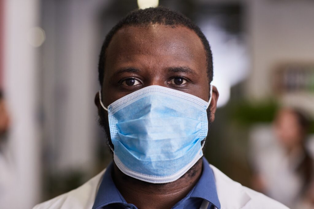 Young serious African-American healthcare worker in protective mask